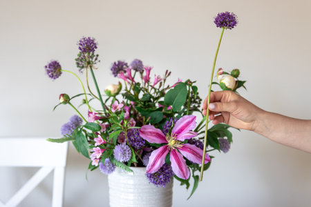 Vase with fresh summer flowers in female hands on a white background.の写真素材