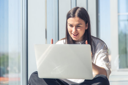 Funny young woman in front of a laptop screen in the office.