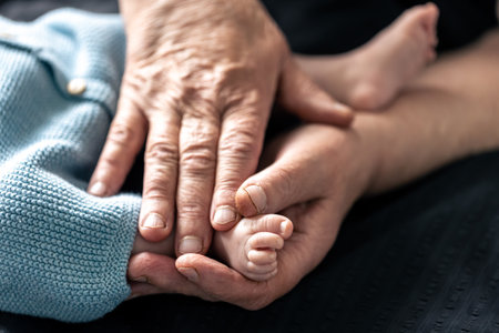 Feet of a newborn baby in the hands of a grandmother, close-up.の写真素材