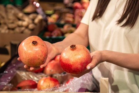 The woman holds pomegranate in the store or in the market, close up.の写真素材