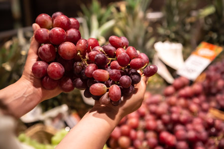 The woman holds bunch of grapes in the store or in the market, close up.