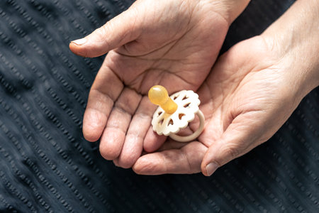 Close-up, a baby pacifier in the hands of a grandmother.の写真素材
