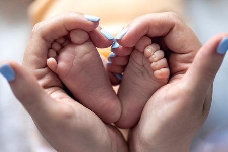 Mom holds the legs of a newborn baby in her hands.の写真素材