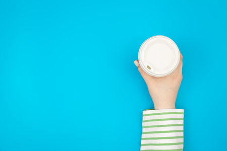 Disposable paper cup in female hand, flat lay.の写真素材