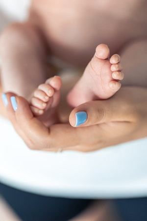 Close-up, the feet of a newborn in the hands of the mother.