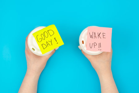 Disposable paper cups with inscriptions Good day and Wake up, top view.