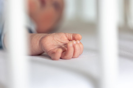 Close-up, the hand of a newborn baby on a blurred background.