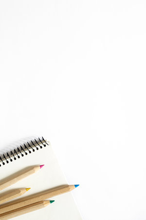 Wooden pencils of different colors and a notebook on a white background.の写真素材