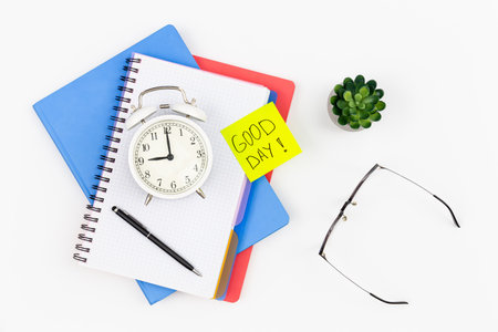 Notebooks, an alarm clock and a paper reminder on a white background isolated.の写真素材