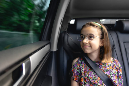 The girl is sitting in the car on the way to school.