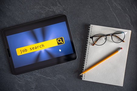 Top view of digital tablet with search job on screen on a table.の写真素材