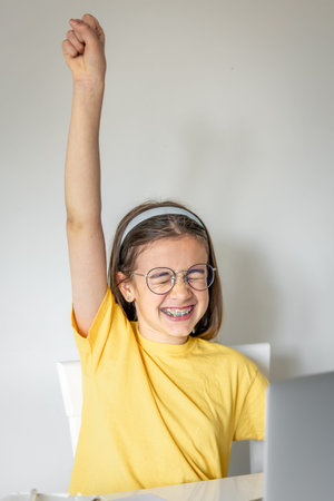 Cute schoolgirl with a laptop studying at home, online learning.