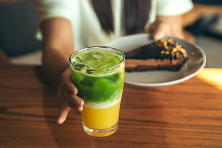 Close-up, lemonade and chocolate cake in female hands.