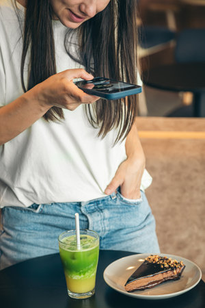 Young woman having breakfast at the cafe indoors, taking a photo, blogging.の写真素材
