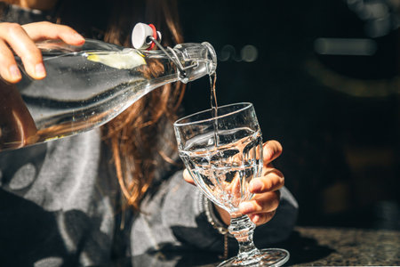 A woman in a cafe pours water into a glass.の写真素材