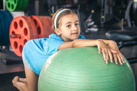 Happy girl stretches her body on a fitball in the gym.の写真素材