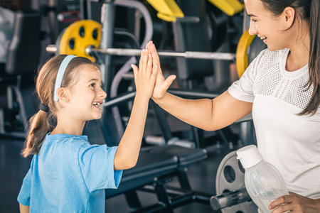 Strong mother and daughter giving high five at gym.の写真素材