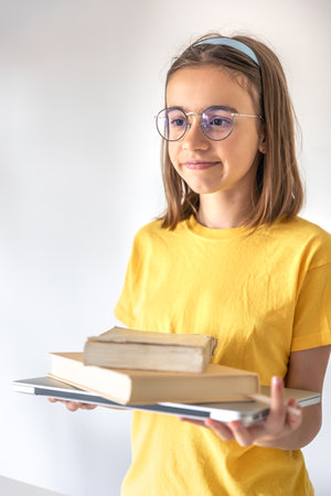 Funny teen girl with books and laptop on the background of a white wall.の写真素材