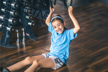 Little girl using trx fitness straps for working with his own weight.の写真素材