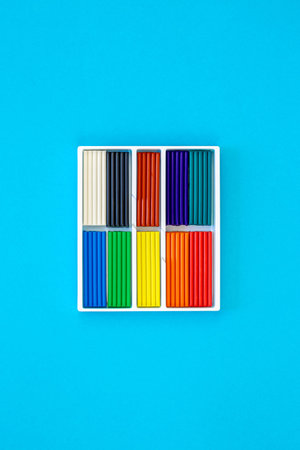 Set of colorful plasticine sticks isolated on a blue background, top view.