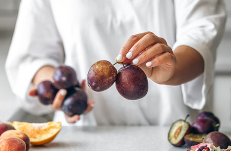 Plums in the hands of a woman in the kitchen.の写真素材