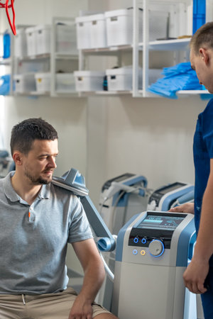 Doctor using machine to treat the patients shoulders.