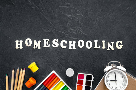 Homeschooling word made of wooden letters on a black background, top view.の写真素材