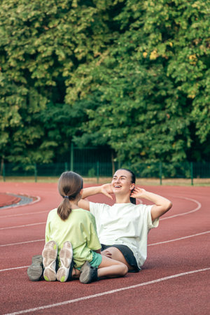 Mother and daughter go in for sports outdoors at the stadium.の写真素材
