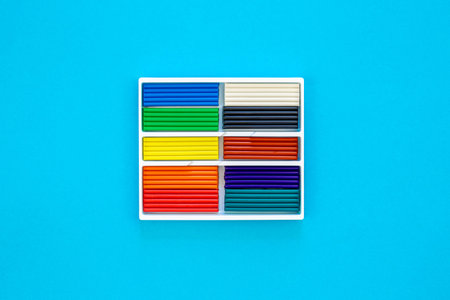 Set of colorful plasticine sticks isolated on a blue background, top view.