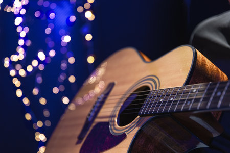 Close-up, acoustic guitar on a dark background with bokeh lights.の写真素材