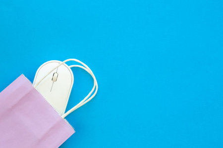 Computer mouse and paper bag on a blue background, top view.の写真素材