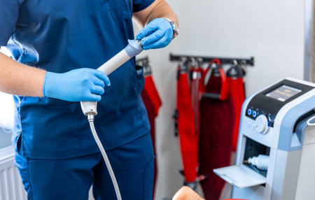 Shock wave therapy device with male doctor hands in rubber gloves.