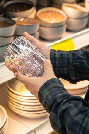 Man holding glass from a shelf in homeware store.の写真素材