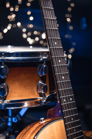 Snare drum and guitar on a blurry dark background with bokeh.