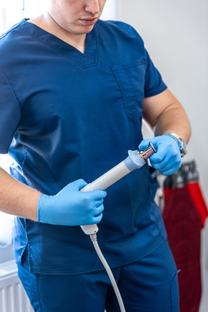 Shock wave therapy device with male doctor hands in rubber gloves.