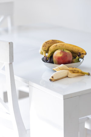 A bunch of ripe bananas and an apple on the kitchen table.の写真素材