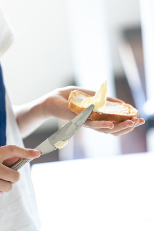A piece of bread with butter in a womans hand.の写真素材