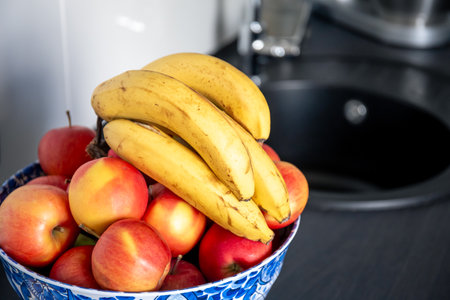 A bunch of bananas and apples in the kitchen near the sink.の写真素材