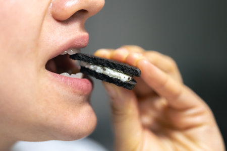 Detailed shot of a woman bites a chocolate cookie.の写真素材