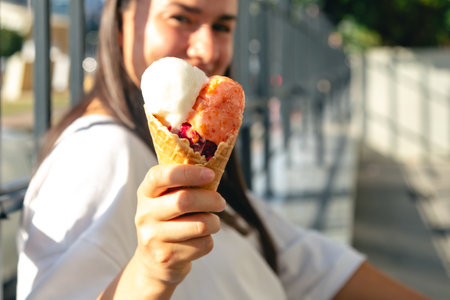 Portrait of happy caucasian brunette woman, eating ice-cream cone.の写真素材
