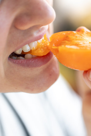 Detailed shot of a woman bites yellow ripe tomato.の写真素材