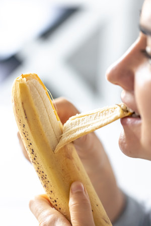 Detailed shot of a woman eats ripe fresh banana.の写真素材