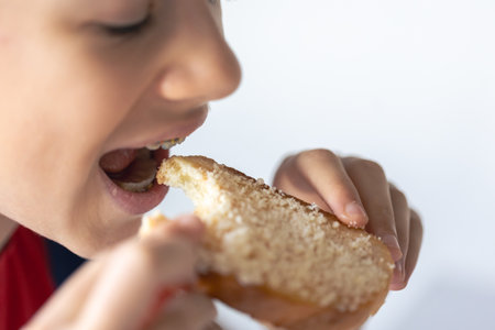 A child eats bread with grated cheese, close-up.の写真素材