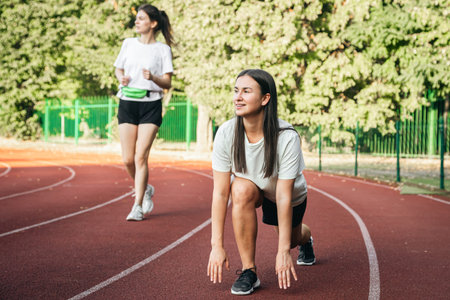 A young woman runner in start position on running track while work out.