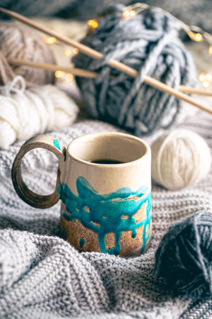 Cozy composition with a cup of coffee, threads and a knitted element.