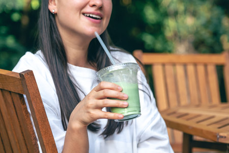 Woman drinking matcha latte, healthy iced drink.の写真素材