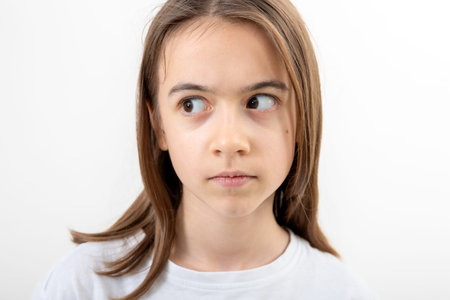 Little girl looks to the side in surprise on a white background isolated.