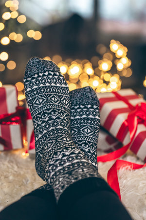 Feet in Christmas socks and gift boxes in front of the fireplace, close up.の写真素材