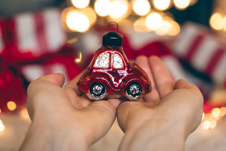 Christmas toy in the shape of a car in female hands on a blurred background.の写真素材