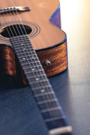 Acoustic guitar, music instrument resting against a dark black background.の写真素材